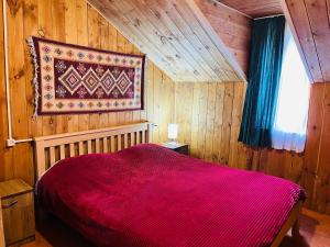 a bedroom with a red bed in a wooden room at Hotel Arkhoti in Akhieli