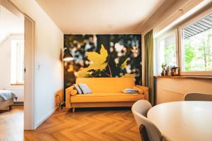 a living room with a yellow couch and a table at Las Apartamenty - z pomostem i prywatnym dostępem do jeziora in Borowy Młyn