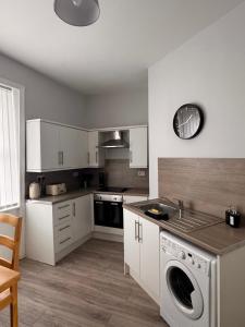 a kitchen with white cabinets and a washer in it at Grantham House - Sleeps 6 - Pet friendly - Parking in Newcastle upon Tyne