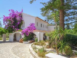 une maison blanche avec des fleurs violettes dans l'établissement Quinta de Lagos, à Lagos