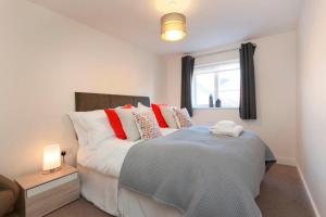 a bedroom with a bed with red and white pillows at DBS Serviced Apartments - The Terrace in Castle Donington