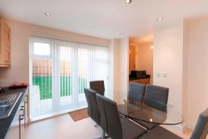 a dining room with a glass table and chairs at DBS Serviced Apartments - The Terrace in Castle Donington