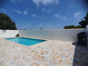 a swimming pool sitting next to a white wall at Chalet Laguna Rosa in Torrevieja
