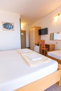 a hotel room with two beds and a desk at Apartmani Ana in Mlini