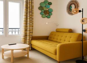 Appartement Splendide Vue sur Tour Eiffel في باريس: غرفة معيشة مع أريكة صفراء وطاولة