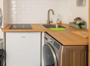 Appartement Splendide Vue sur Tour Eiffel في باريس: مطبخ مع حوض وغسالة ملابس