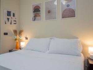 a white bed in a room with pictures on the wall at Spazio Breda - Free Parking, Private Garage, Metro M1, Balcony, 4 Guests in Milan
