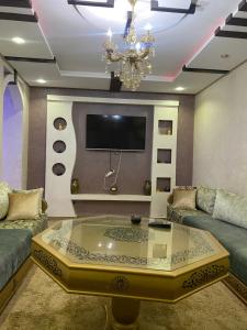 een woonkamer met een tv en een glazen salontafel bij Av des far agadir in Agadir