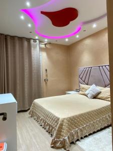 een slaapkamer met een groot bed en een roze plafond bij Av des far agadir in Agadir