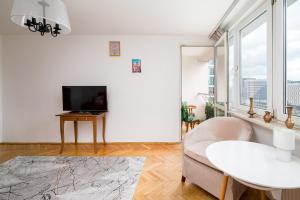 a white living room with a white couch and a tv at 8th Floor City View Apartment by BookingHost in Warsaw