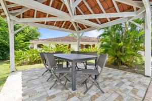 une table et des chaises sous une pergola sur une terrasse dans l'établissement Villa Diamantina, au Diamant
