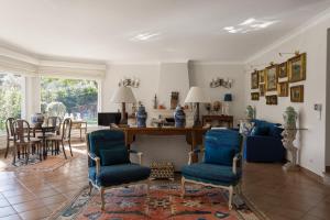 a living room with blue chairs and a table at Villa in Sesimbra Pool Tennis Breakfast in Sesimbra