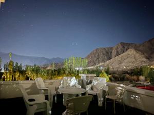 a group of white chairs and tables at night at Skyline Homestay in Leh