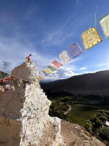 a person sitting on top of a mountain with prayer flags at Skyline Homestay in Leh +16 photos
