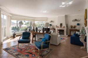 a living room with blue chairs and a table at Villa in Sesimbra Pool Tennis Breakfast in Sesimbra
