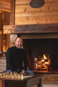 a man sitting in front of a fireplace at Le chalet de Nicolas - Your Nature Exclusive Retreat ! in Le Tholy