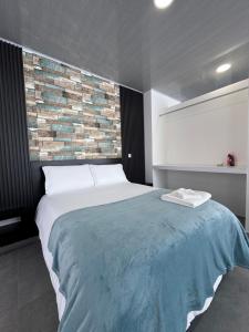 a bedroom with a large bed and a brick wall at Sky Suite in Sogamoso