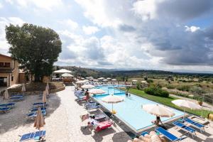 a pool at a hotel with chairs and umbrellas at Apartments in Magliano in Toscana - Maremma-Küste 48277 in Magliano in Toscana