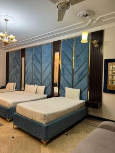 two beds in a room with blue walls at Arizona Lodge Guesthouse in Islamabad