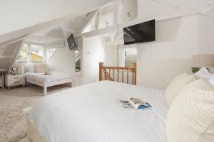a bedroom with a white bed with a tv on the wall at Fond Memories Cottage, The Digey, St Ives in St Ives