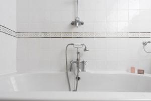 a white bath tub with a shower in a bathroom at Fond Memories Cottage, The Digey, St Ives in St Ives +16 photos