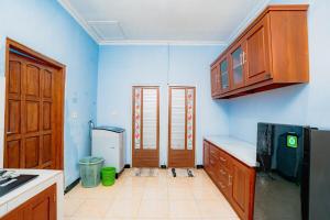 a kitchen with blue walls and wooden cabinets at Guesthouse Andalusia Gontor 1 Ponorogo in Ponorogo