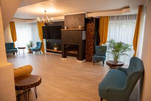 Una sala de estar con chimenea y sillas azules. en Pensiunea Între Prieteni, en Bod