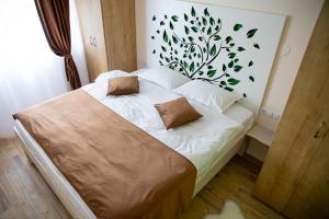 1 dormitorio con 1 cama con hojas en la pared en Pensiunea Între Prieteni, en Bod