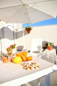 une table blanche avec un parasol et de la nourriture dessus dans l'établissement Appartamento L'airone Balestrate, à Balestrate