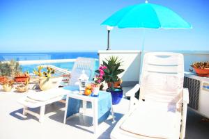 um pátio com 2 cadeiras e uma mesa com um guarda-sol em Appartamento Il Gabbiano Balestrate em Balestrate mais 32 fotografias