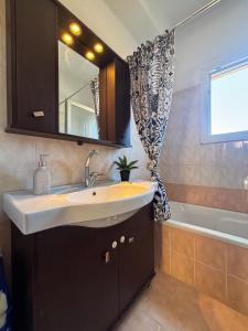 un bagno con un lavandino, uno specchio e una vasca di F&K House Kastania ad Alepoú Altre 30 foto