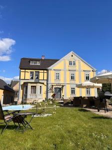 a large yellow house with a yard with chairs at CG Haensch in Großschönau