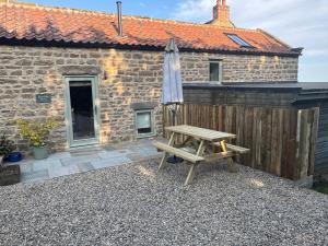 mesa de picnic de madera con sombrilla y banco en Rawcliffe Barn, 2 Bedroom, up to 4 Guests, en Newton