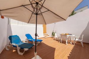 a room with chairs and a table with an umbrella at Alegria's House in Odiáxere