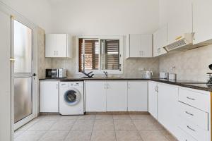 a kitchen with white cabinets and a washing machine at Coral Bay Avenue Villa by Vichy Holidays in Paphos +23 photos