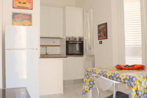 a kitchen with a table and a white refrigerator at AP Apartment - Baia Verde in Baia Verde