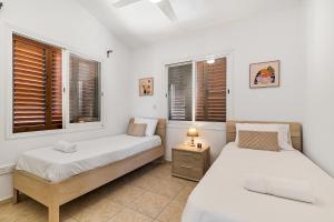 two beds in a room with two windows at Coral Bay Avenue Villa by Vichy Holidays in Paphos