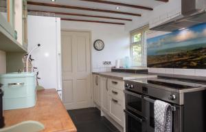 a kitchen with white cabinets and a stove top oven at Bayvil Newport, Pembrokeshire in Nevern