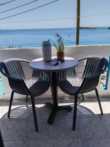 a table and two chairs with the ocean in the background at Notos Rooms in Loutro