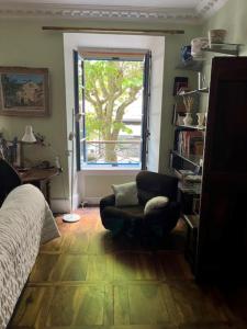 a bedroom with a bed and a chair and a window at Grand appartement de charme avec parking privé in Florac
