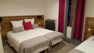 a bedroom with two beds with red pillows at Hotel Du Clocher in Chamonix