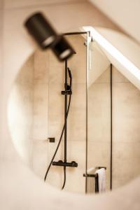a shower in a bathroom with a microphone at Las Apartamenty - z pomostem i prywatnym dostępem do jeziora in Borowy Młyn +90 photos