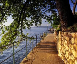 a sidewalk next to the water next to a stone wall at Apartment Sea Garden in Ičići
