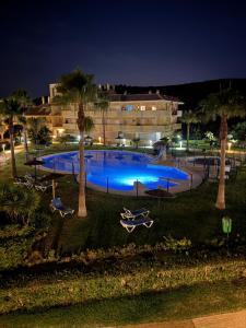 a swimming pool at night with palm trees and a building at Apartamento Vacacional Sol y Mar in Manilva