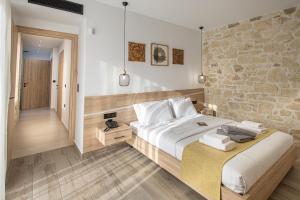 a bedroom with a large bed and a stone wall at Sun and Sea Cretan Hospitality in Pitsidia