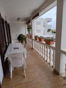 une table et des chaises blanches sur un balcon avec des plantes dans l'établissement Gama, à Vir