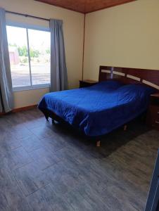 a bedroom with a bed and a large window at Cabañas Hamdan villa residencial laguna brava in Balcarce