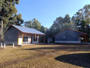 a house with a garage next to a field at Cabañas Hamdan villa residencial laguna brava in Balcarce