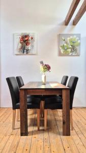 einen Holztisch mit Stühlen und eine Vase mit Blumen darauf in der Unterkunft Loft Timonova, Košice - Old Town in Košice