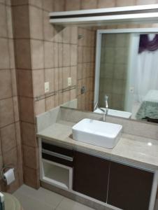 un baño con lavabo y espejo en Apartamento Quadra Mar Meia Praia, en Itapema